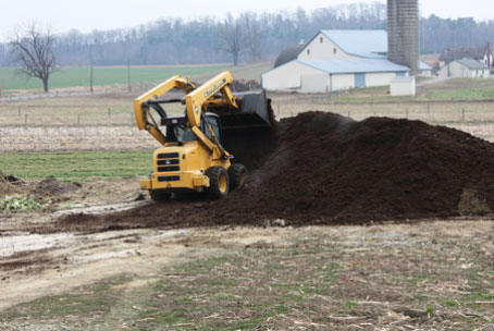 Turning over brown gold compost. We work hard to reduce our fertilizer use on your veggies.